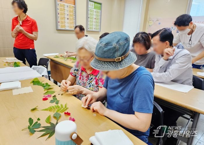 지난 5일 광명시 구름산 둘레길에서 야외치유프로그램에 참여한 어르신들과 보호자들이 함께 꽃과 잎을 활용한 천연염색 손수건 만들기를 하고 있는 모습.