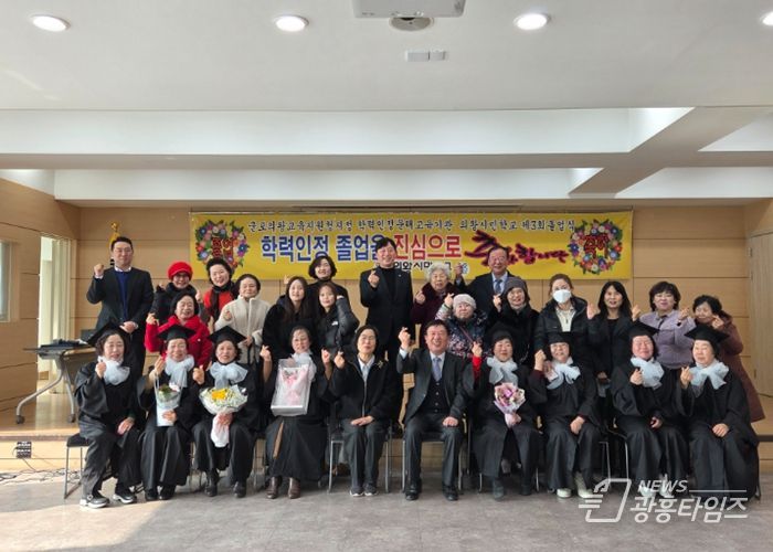 졸업생(의왕시민학교, 의왕시청)들이 학사모를 쓰고 환하게 웃으며 단체 기념사진을 촬영하고 있다.